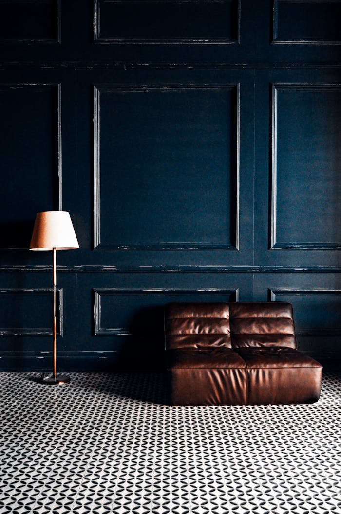 Interior of contemporary apartment with soft leather sofa and lamp against blue wall